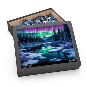 May include: A 252 piece jigsaw puzzle featuring a snowy landscape with a lake reflecting the aurora borealis in the sky. The box is open and the puzzle pieces are visible inside. The box has the text "11x14 Puzzle 252 pcs Ages 9+"