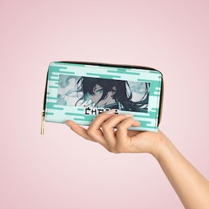 Op de afbeelding: Een lichtblauwe portemonnee met een gouden rits, met een anime-achtige illustratie van een personage met zwart haar en blauwe ogen. Het woord "CHASE" is in het wit gedrukt. De portemonnee wordt in een hand gehouden.