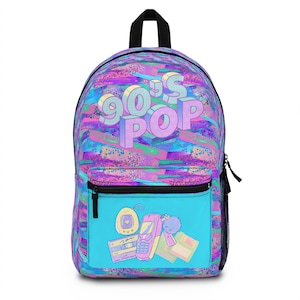 Può includere: Uno zaino con un vivace design Pop anni '90. Il corpo principale presenta un colorato motivo a pennellate rosa, blu e viola. La tasca frontale ha uno sfondo turchese con grafica a tema anni '90, tra cui una musicassetta, un telefono cellulare e un Tamagotchi.