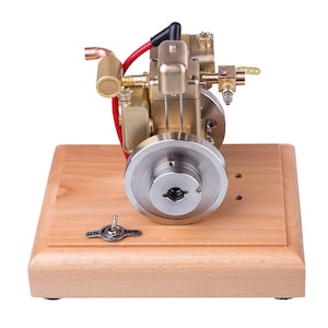 May include: A miniature model engine with brass and silver components, mounted on a wooden base. The engine features a flywheel, wiring, and a toggle switch labeled "ON" and "OFF". The base is approximately 6 inches long.