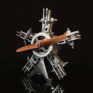 May include: A detailed metal model of a radial aircraft engine. The model features a brown propeller, silver gears, and cylinders. The engine is mounted on a black base, showcasing intricate mechanical details.