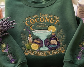 May include: A forest green crewneck sweatshirt featuring intricate embroidery of a margarita glass, books, a candle, and limes. The text reads "PUT THE LIME IN THE COCONUT", "MIDNIGHT MARGARITAS", "WITCHES SPIRITS", and "AND DRINK IT ALL UP". Sleeves have matching motifs.