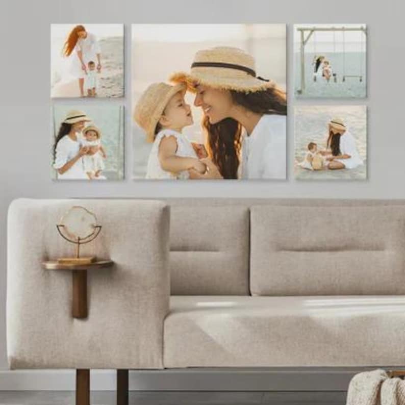 Pu&ograve; includere: Un'esposizione di arte murale con sei stampe su tela di una madre e un bambino. Le stampe mostrano la coppia su una spiaggia, con cappelli di paglia e abiti bianchi. Le stampe sono montate sopra un divano beige.