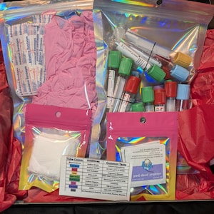 May include: A medical kit with various supplies, including pink gloves, adhesive bandages, and blood collection tubes with colored stoppers. The kit also contains alcohol prep pads and a chart detailing tube colors, additives, and common tests.