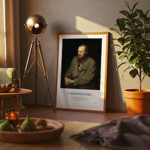 May include: A framed portrait of F. Dostoevsky, with a wooden frame, leans against a wall. The portrait features a man with a beard and a coat. The text "F. DOSTOEVSKY" is at the bottom. A gold floor lamp and a potted plant are also in the room.