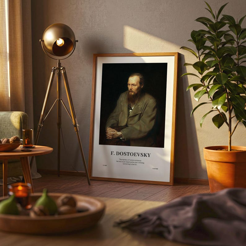 May include: A framed portrait of F. Dostoevsky, with a wooden frame, leans against a wall. The portrait features a man with a beard and a coat. The text "F. DOSTOEVSKY" is at the bottom. A gold floor lamp and a potted plant are also in the room.