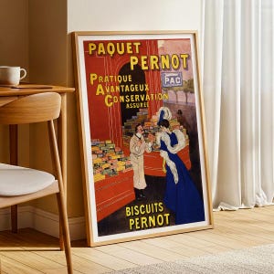 Puede incluir: Póster publicitario vintage enmarcado de "Biscuits Pernot". El póster presenta una combinación de colores rojo y amarillo con texto en francés. Representa a un hombre y una mujer con ropa de época, con pilas de cajas de galletas.