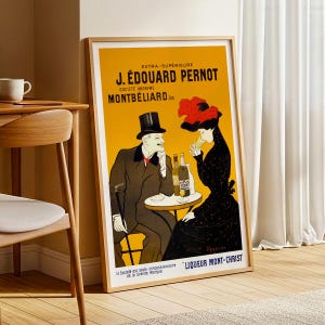 Puede incluir: Póster publicitario vintage enmarcado de licor J. Édouard Pernot. El póster presenta una pareja en una mesa, botellas y texto en francés. El fondo es amarillo, con un marco de madera.