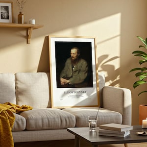 May include: A framed portrait of F. Dostoevsky, featuring a man with a beard and wearing a green coat. The artwork is displayed on a wall above a beige sofa. The text "F. DOSTOEVSKY" is printed at the bottom of the artwork.