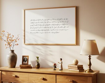 May include: A wooden framed print with handwritten text hangs above a wooden console table. The table displays a vase with branches, a framed photo, a small plant, figurines, books, and a lamp.