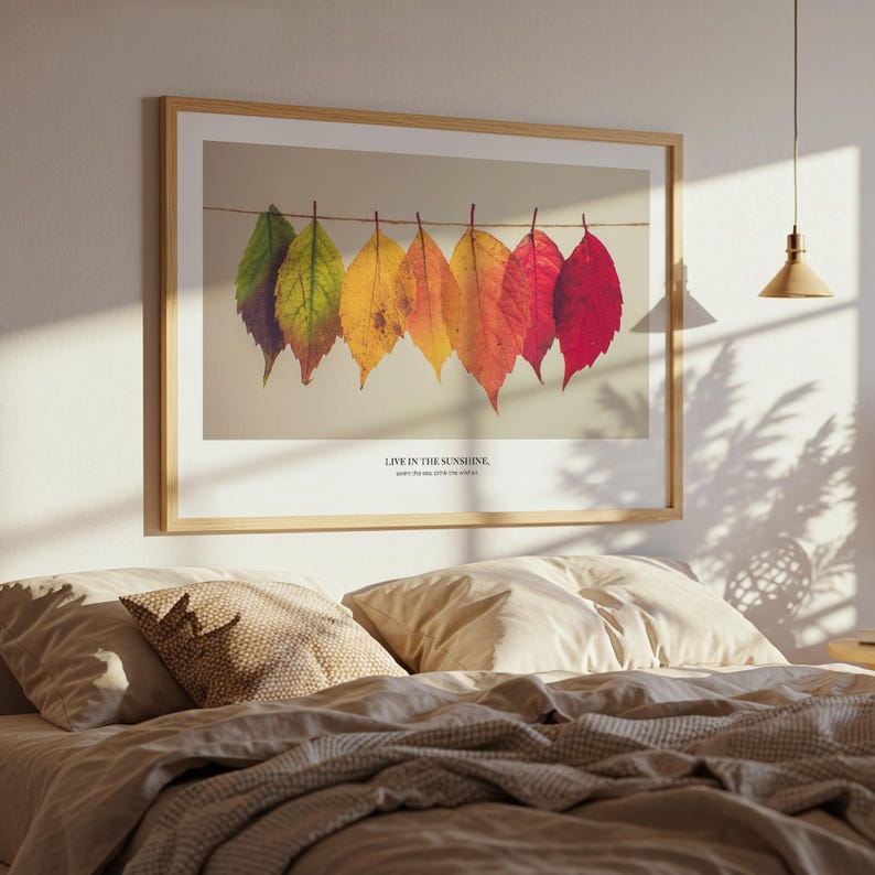 Puede incluir: Un cuadro enmarcado con hojas de oto&ntilde;o coloridas colgadas de una cuerda. Las hojas var&iacute;an de verde a rojo, con el texto "LIVE IN THE SUNSHINE, watch the stars, swim in the wild girl."