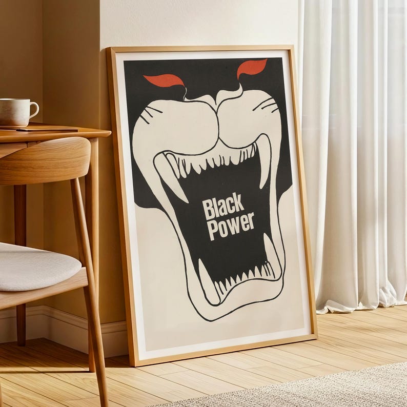 May include: A framed poster with a bold graphic design. The artwork features a black panther-like face with an open mouth, displaying sharp white teeth. The words "Black Power" are centered in the mouth. Red accents are above the eyes.