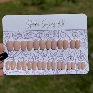 May include: A "Starter Sizing Kit" with a variety of nude-colored press-on nails. The kit includes nails in sizes 00 through 9, with a glittery finish. The card has a floral design and the text "Starter Sizing Kit".