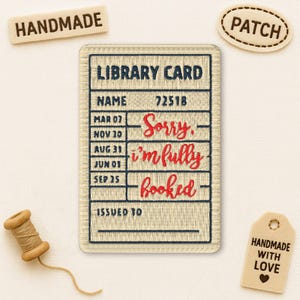May include: Embroidered library card patch with the text "Sorry, I'm fully booked" in red script. The patch is beige with navy blue text and stitching. Includes a "Handmade" wooden tag and a spool of thread.