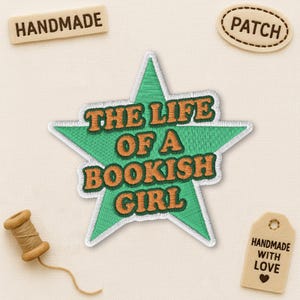May include: A green star-shaped patch with the text "THE LIFE OF A BOOKISH GIRL" in orange embroidery. The patch is surrounded by a white border. Additional elements include a "HANDMADE" label, a "PATCH" label, a spool of thread, and a "HANDMADE WITH LOVE" tag.