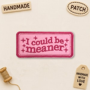 Peut inclure: Un écusson rose brodé avec le texte "I could be meaner". Le patch rectangulaire a une bordure rose foncé et des étoiles. D'autres étiquettes indiquent "HANDMADE", "PATCH" et "HANDMADE WITH LOVE".