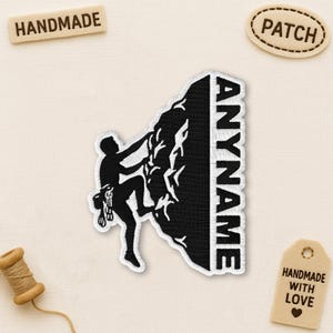 May include: Black and white embroidered patch featuring a rock climber ascending a mountain. The patch includes the text "ANYNAME" and is labeled "PATCH" and "HANDMADE". A tag reads "HANDMADE WITH LOVE".