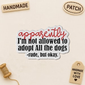May include: Embroidered patch with the text "apparently I'm not allowed to adopt All the dogs - rude, but okay." Also includes a "patch" and "handmade" tag. A spool of thread is in the image. The patch is white with black text and red accents.