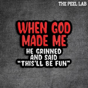 May include: Embroidered patch with the text "WHEN GOD MADE ME HE GRINNED AND SAID 'THIS'LL BE FUN'" in red and white on a black background. The patch is on a gray denim fabric. The Peel Lab logo is at the top.