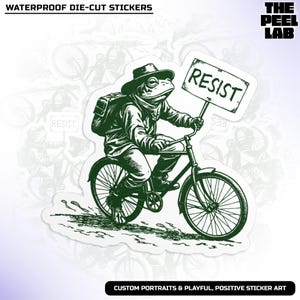 May include: A die-cut sticker featuring a frog riding a bicycle and holding a sign that says "RESIST." The frog is wearing a hat and backpack. The sticker has the text "WATERPROOF DIE-CUT STICKERS" and "CUSTOM PORTRAITS & PLAYFUL, POSITIVE STICKER ART".
