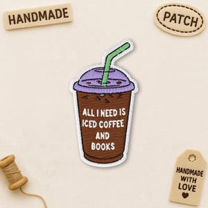 May include: Embroidered patch of a brown iced coffee cup with a purple lid and green straw. The text "ALL I NEED IS ICED COFFEE AND BOOKS" is displayed on the cup. Other patches and a thread spool are also visible.