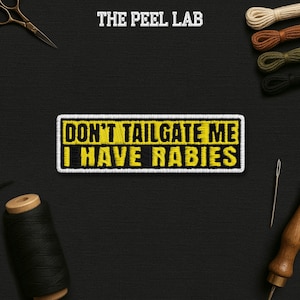 May include: Embroidered patch with the text "DON'T TAILGATE ME I HAVE RABIES" in yellow and black, outlined in white. The patch is rectangular and features a black background with sewing tools and thread.