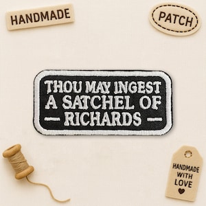 May include: A black and white embroidered patch with the text "THOU MAY INGEST A SATCHEL OF RICHARDS" is surrounded by other handmade items. The patch is rectangular with rounded corners. Other items include a wooden "HANDMADE" sign and a "PATCH" sign.