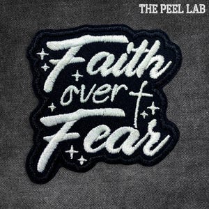 May include: A black embroidered patch with the words "Faith over Fear" in white script. The patch has a dark blue border and small star accents. The text "THE PEEL LAB" is at the top.