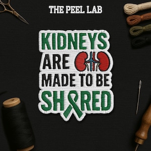 May include: Embroidered patch with the text "KIDNEYS ARE MADE TO BE SHARED" in green and white. The design includes a red and blue kidney graphic and a green ribbon. The Peel Lab logo is at the top.