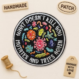 May include: A black embroidered patch with the text "WHAT DOESN'T KILL YOU MUTATES AND TRIES AGAIN" surrounding a colorful microbe design. Includes a "PATCH" tag and a "HANDMADE" tag.