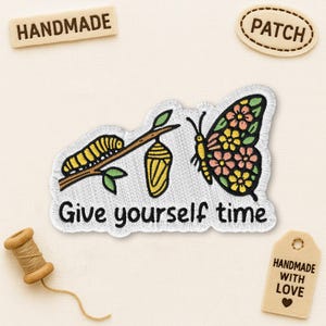 May include: Embroidered patch featuring a caterpillar, chrysalis, and butterfly with floral wing details. The patch includes the text "Give yourself time." Additional tags read "Handmade" and "Patch."