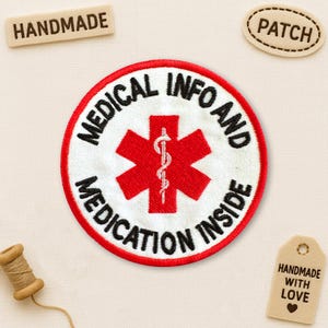 May include: A round, embroidered patch with the text "MEDICAL INFO AND MEDICATION INSIDE" in black on a white background, encircled by a red border. A red star of life symbol is in the center. Additional tags read "HANDMADE" and "PATCH".