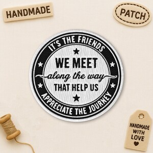 May include: A round, black and white patch with the text "IT'S THE FRIENDS WE MEET along the way THAT HELP US APPRECIATE THE JOURNEY". Includes a small wooden tag that says "HANDMADE WITH LOVE". Also includes a wooden tag that says "HANDMADE".
