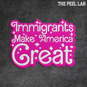 May include: A pink embroidered patch with the text "Immigrants Make America Great" in white script. The patch has a decorative border and is set against a dark gray fabric background. The Peel Lab logo is in the top right corner.