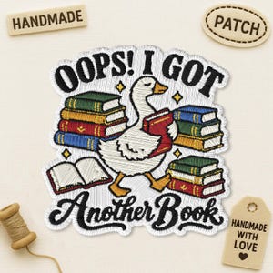 May include: An embroidered patch featuring a white goose holding a red book, surrounded by stacks of colourful books and an open book. The text reads OOPS! I GOT Another Book in black thread. The design includes small yellow stars on a white background.