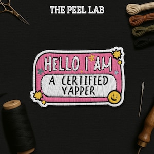 May include: Embroidered patch with the text "HELLO I AM A CERTIFIED YAPPER" in pink, white, and yellow. The patch has a pink border and a smiling face. The Peel Lab logo is at the top.