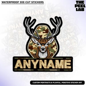 May include: A die-cut sticker with a detailed illustration of a deer with large antlers. The deer is set against a camouflage background. The sticker includes the text "ANYNAME" and "WATERPROOF DIE-CUT STICKERS".