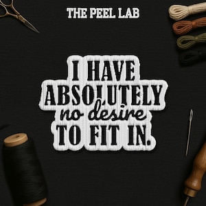 May include: A black and white embroidered patch with the text "I HAVE ABSOLUTELY no desire TO FIT IN." The patch is surrounded by sewing tools and spools of thread, including scissors, needles, and a wooden handle.