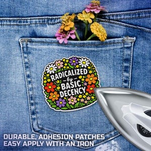 May include: A colourful patch with the text "RADICALIZED -by- BASIC DECENCY" surrounded by flowers, placed on a denim pocket. The pocket contains a small bouquet of flowers. An iron is in the lower right corner. The patch is a durable, adhesion patch.