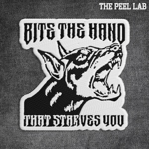May include: Embroidered patch with the text "Bite the Hand That Starves You" and a snarling dog graphic in black and white. The patch has a white border and is set against a gray fabric background. The Peel Lab logo is at the top.