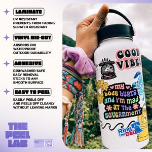 May include: A white water bottle covered in colorful stickers, including one that says "GOOD VIBES." Other stickers read "my body hurts and I'm mad at The government." The bottle is held by a person wearing a bracelet. The Peel Lab stickers are also visible.