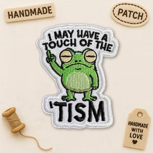 May include: Embroidered patch featuring a green frog with the text "I MAY HAVE A TOUCH OF THE 'TISM". The patch has a white border. Additional tags read "HANDMADE", "PATCH", and "HANDMADE WITH LOVE".