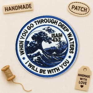 May include: A circular, navy blue and white embroidered patch with the text "WHEN YOU GO THROUGH DEEP WATERS, I WILL BE WITH YOU" and "ISAIAH 43:2". The patch features a wave design. Handmade tags and a spool of thread are also visible.