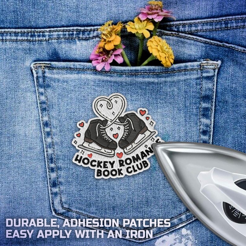 Puede incluir: Un bolsillo de mezclilla con un parche de patines de hielo, corazones y el texto "Hockey Roman Book Club". Hay una plancha al lado. El texto "Durable, Adhesion Patches, Easy Apply With An Iron" est&aacute; en la parte inferior. Hay flores en el bolsillo.