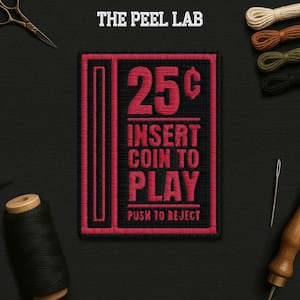May include: A black and red embroidered patch with the text "25¢ INSERT COIN TO PLAY PUSH TO REJECT". The patch is rectangular with a retro arcade game theme. The Peel Lab is printed at the top.