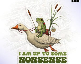May include: A die-cut sticker featuring a whimsical illustration of a frog riding a goose. The frog is holding reins, and the goose is adorned with a red harness. The sticker has the text "I AM UP TO SOME NONSENSE".