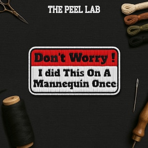 May include: A rectangular patch with the text "Don't Worry! I did This On A Mannequin Once" in black and white, with a red and white border. The Peel Lab logo is at the top. Sewing supplies are in the background.