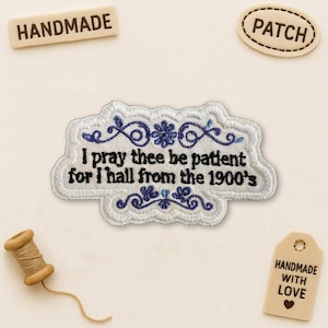 May include: Embroidered patch with the text "I pray thee be patient for I hall from the 1900's" in black and blue. The patch has a white border with blue floral accents. Additional tags read "HANDMADE", "PATCH", and "HANDMADE WITH LOVE".