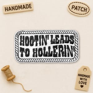 May include: A white embroidered patch with the text "HOOTIN' LEADS TO HOLLERIN'" in black, framed by a black and white rope design. The image also includes small wooden tags that say "HANDMADE", "PATCH", and "HANDMADE WITH LOVE".