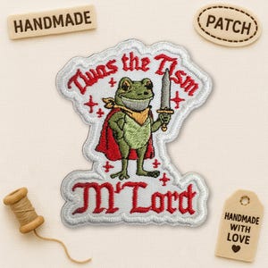 Peut inclure: Écusson brodé représentant une grenouille verte portant une cape rouge et tenant une épée. Le patch porte l'inscription "'Twas the Tism M'Lord" en rouge. Les étiquettes supplémentaires indiquent "Handmade" et "Patch".